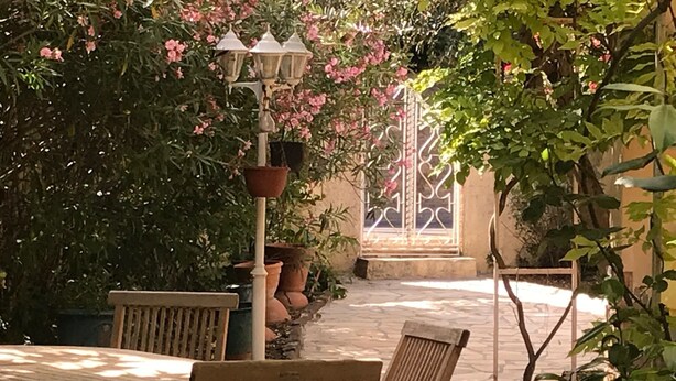 Un espace extérieur aménagé en terrasse, avec des meubles en bois, des plantes en pot et un lampadaire décoratif.