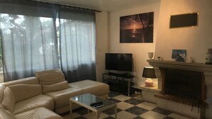 Un salon avec un canapé, un téléviseur, une cheminée et un sol à carreaux.
