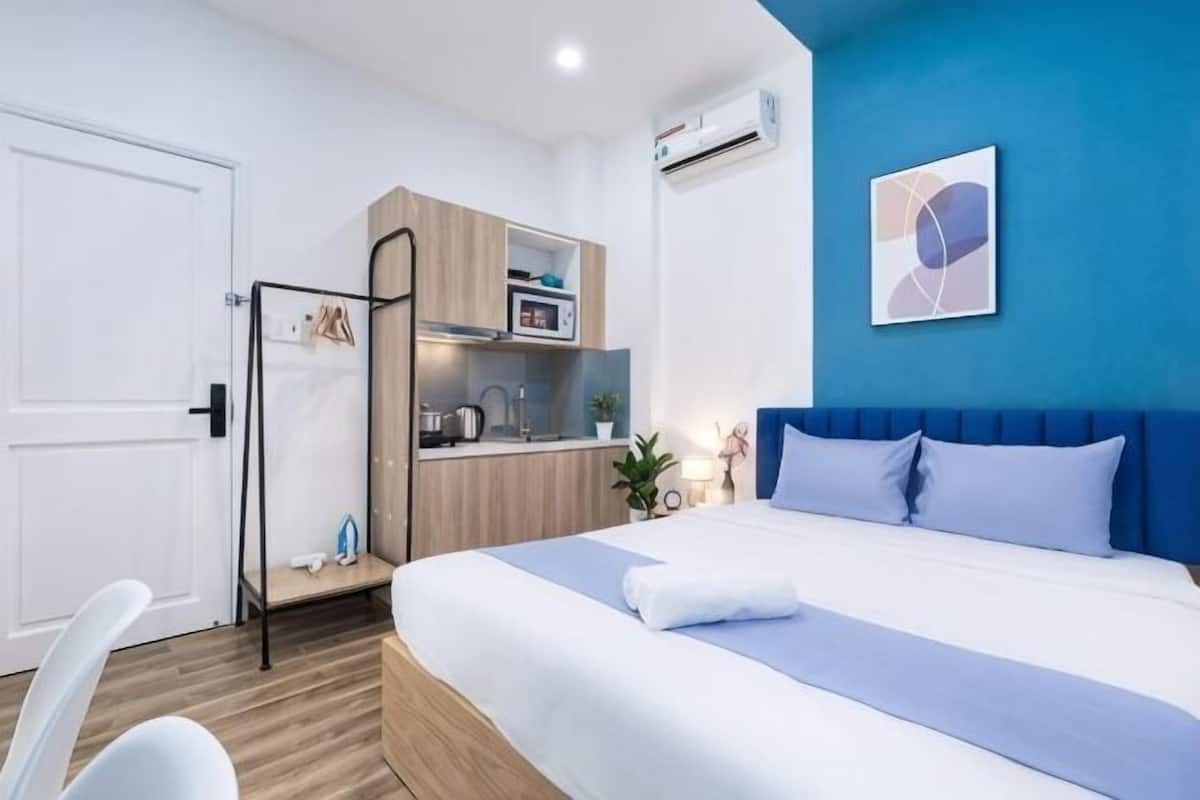 Een slaapkamer met een bed, een bureau, een kitchenette en een badkamer.