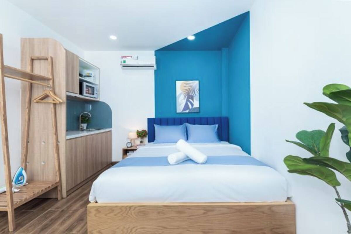 Ein modernes Hotelzimmer mit Bett, Kleiderschrank, Schreibtisch und Wandairconditioner.