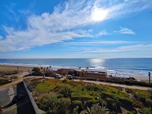 A coastal hotel with a beach view, a parking area, and a landscaped garden.