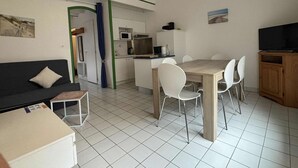 Kompakti oleskelutila, jossa on pieni keittiö, ruokailualue ja sohva.