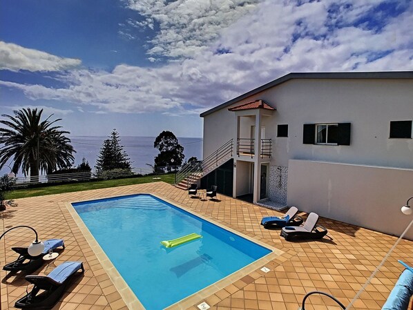 A swimming pool with lounge chairs and a view of the sea. - Villa Prainha by LovelyStay (Canical)