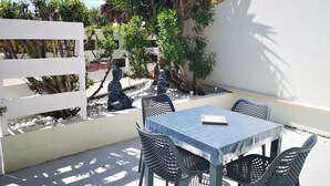 A patio with a table and chairs, surrounded by plants and a Buddha statue.