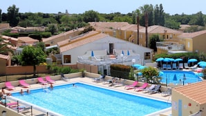 A rectangular swimming pool with multiple lanes, surrounded by lounge chairs and umbrellas.