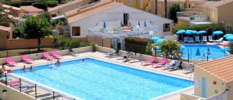 A rectangular swimming pool with multiple lanes, surrounded by lounge chairs and umbrellas.