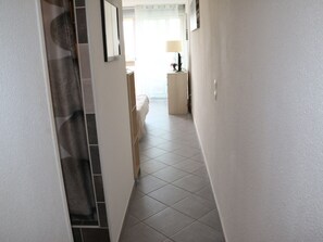 A narrow hallway with tiled flooring, a white wall, and a door with a patterned curtain. - Studio for 2 with terrace and parking, Cap d'Agde (Cap d'Agde naturisme)