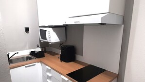 Uma cozinha compacta com micro-ondas, cafeteira e pia.