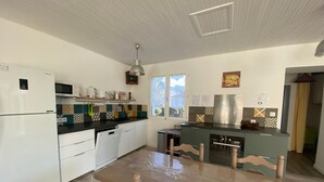 Une cuisine moderne avec des appareils électroménagers blancs, une table à manger en bois et des carreaux à motifs.