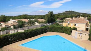 A rectangular swimming pool with a tiled deck, surrounded by a low brick wall and a metal fence. - Charming Studio with Pool Access, Terrace, and Parking in Agde (Cap d'Agde naturisme)