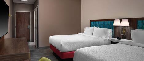A hotel room with two beds, a desk, a television, and a door.