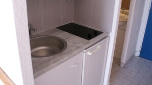 A compact kitchen with a built-in stove, a sink, and a microwave on a shelf.