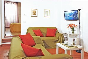 Un soggiorno con divano, tavolino, televisione e un vaso con fiori.