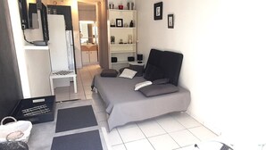 Ett kompakt hotellrum med en säng, ett skrivbord, en stol och en garderob.
