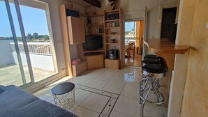 Ett kompakt bostadsutrymme med en balkong, ett litet kök och en matplats.