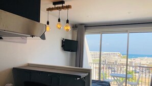 Una stanza moderna con angolo cottura, un balcone con vista sulla città e un letto.