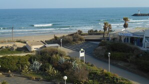 Vista costera con playa, un faro y un edificio que dice 'L'horizon'.