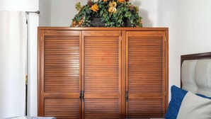 Un dormitorio con una cama, un armario de madera y un arreglo floral encima.