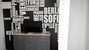 A room with a grey cabinet and a black TV on top. - Urban Zebra Modern Studio in Donizetti Residence (Bergamo)