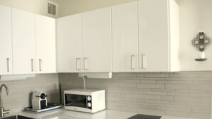 A modern kitchen with white cabinets, a microwave, a sink, and a black countertop. - Charming Villa in Agde: 2BR, A/C, Private Terrace, WiFi, Parking (Cap d'Agde naturisme)
