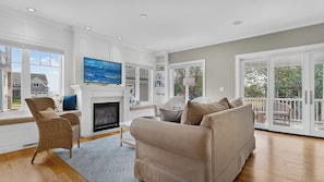 A spacious living room with a fireplace, large windows, and a view of the outside.