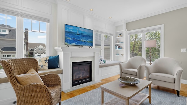A living room with a fireplace, a television, wicker furniture, and a view of the outside. - Happy Holidays with Sea Breeze (Scarborough)