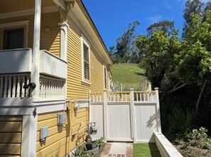 A yellow house with a white porch and a white fence.