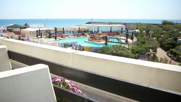 A resort with a pool area, a view of the ocean, and a balcony with flowers. - Air-conditioned apartment for 2 in Cap d'Agde (Cap d'Agde naturisme)