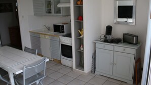 Eine kleine Küche mit weißen Schränken, einer Mikrowelle, einem Toaster und einer Kaffeemaschine.