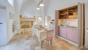 Une cuisine spacieuse avec un coin repas, dotée d’un sol en pierre, de meubles en bois et d’un four encastré.