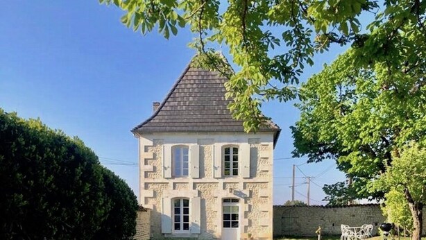 Een twee verdiepingen tellend stenen huis met een grindpad dat naar de ingang leidt.