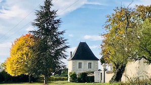 Een huis met een steil dak, omgeven door een verzorgd gazon en bomen met herfstkleuren.