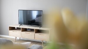 Un salon moderne avec un téléviseur à écran plat posé sur un meuble télé en bois, un canapé et une table basse.