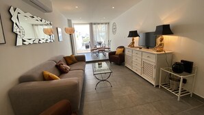 Ein modernes Wohnzimmer mit einer Couch, Sesseln, einem Couchtisch, einem Fernseher und einem Schrank.