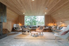 A cozy log cabin interior with a large window, wooden walls, and a comfortable seating area with sofas and chairs. - Welcome to The A-Frame Villa (Åre SV)