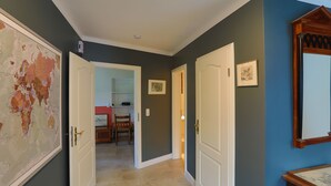 A hallway with a large world map, a door leading to a kitchen, and a mirror on the right wall. - Idyllic apartment with a view of the water (Preußisch Oldendorf)