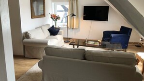 A living room with a sofa, armchair, and a coffee table. - Idyllic apartment with a view of the water (Preußisch Oldendorf)