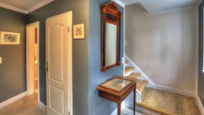 A hallway with a wooden door, a small table with a mirror, and a staircase. - Idyllic apartment with a view of the water (Preußisch Oldendorf)