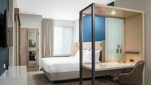 Een hotelkamer met een bed, bureau, stoel en een grote spiegel.
