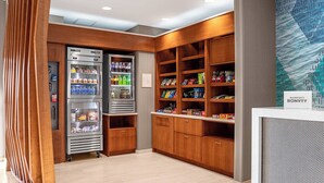Een hotel lobby met houten planken vol snacks en een drankautomaat.