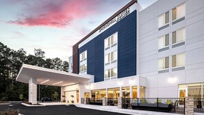 Een modern hotel met een overdekte ingang, grote ramen en een bord met de tekst 'Springhill Suites'.