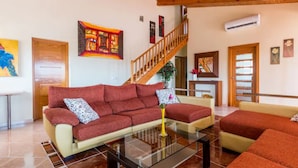 A living room with a red sofa, a glass coffee table, and a wooden staircase. - PRIVATE VILLA WITH POOL VALLADA.No for rent to under 25 years old for S.Joan (ciutadella de menorca)