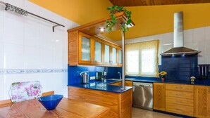 A kitchen with wooden cabinets, a blue countertop, a stainless steel dishwasher, and a window with a view. - PRIVATE VILLA WITH POOL VALLADA.No for rent to under 25 years old for S.Joan (ciutadella de menorca)
