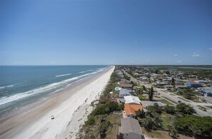 A coastal town with a long beach, houses, and a clear sky.