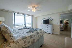 A bedroom with a bed, a ceiling fan, a TV, and a dresser.