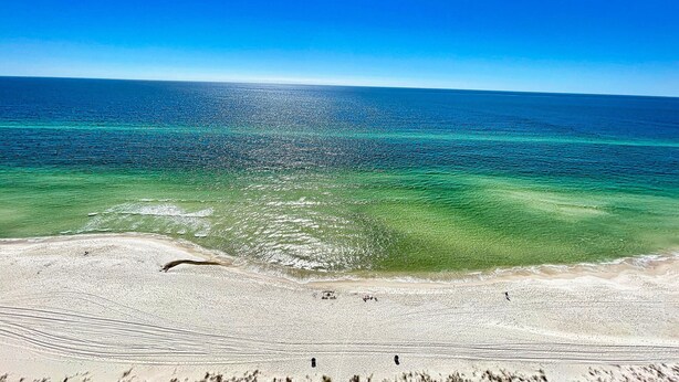 Une plage avec une eau turquoise cristalline et un rivage sablonneux.