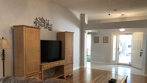 Un soggiorno con televisore, mobili in legno, un divano e un tavolino.