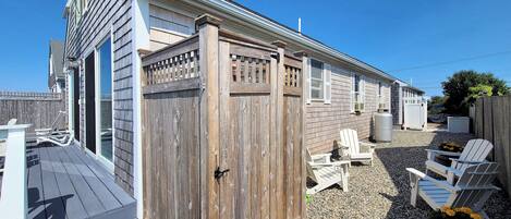 A wooden deck with Adirondack chairs, a grill, and a large water tank.