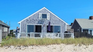 A beach house with a white deck, large windows, and a small porch. - Waterfront 2BD Cottage: RIGHT ON THE BEACH, Water View, Direct Beach Access, A/C & Exclusive Use Deck (North Truro)