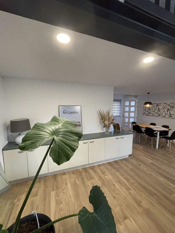 A modern kitchen with a large island, a dining area with a table and chairs, and a framed picture on the wall.
